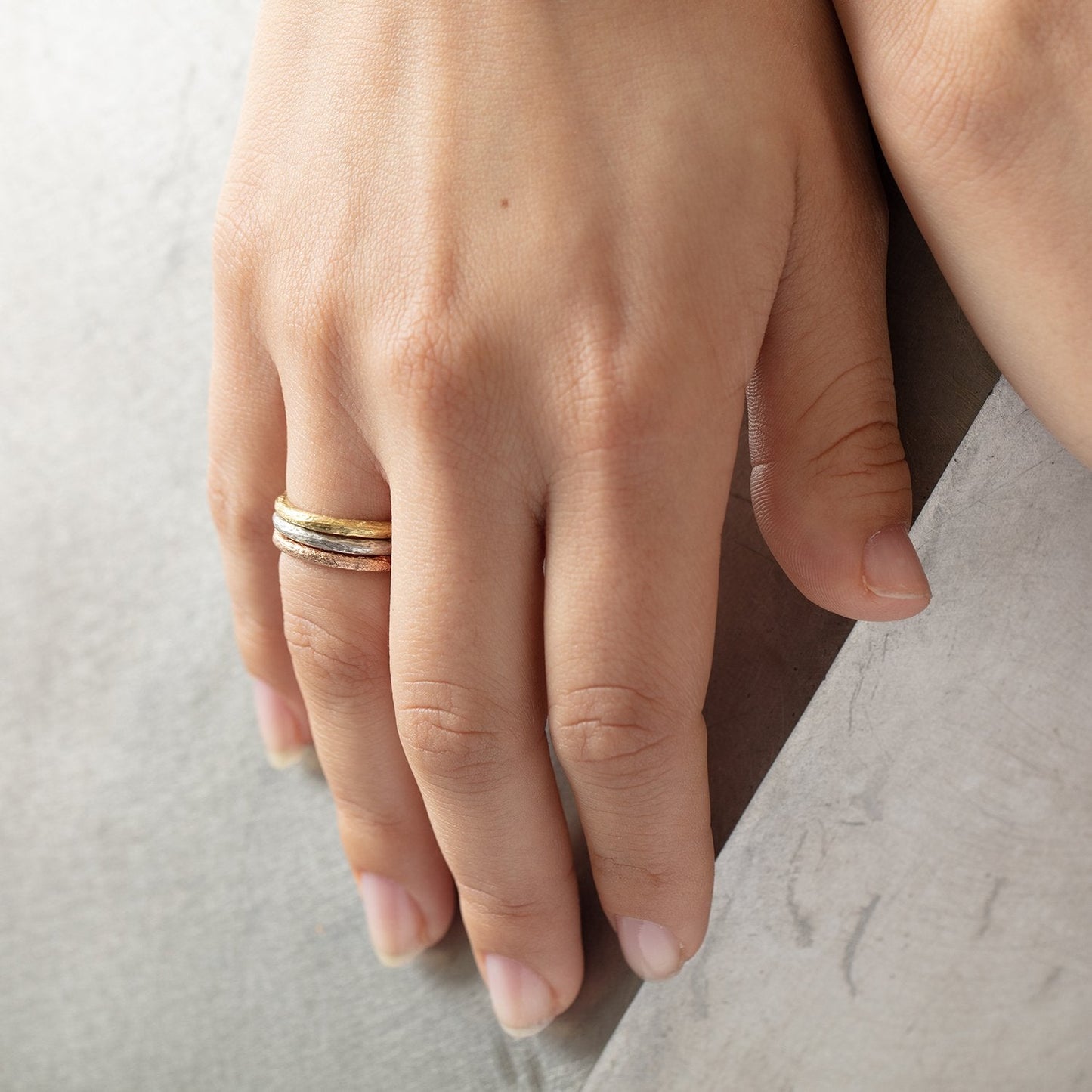 Stacked set of 3 Lu Bands by Betsy Barron, worn on model's right hand.