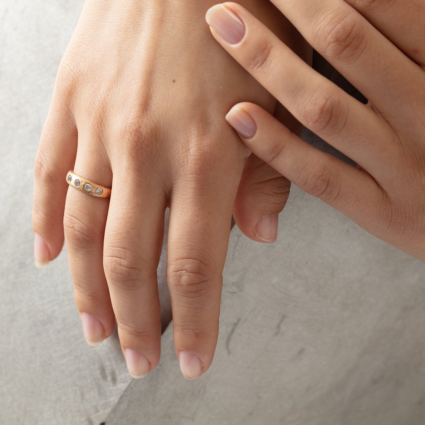 Narrow Molten Band in 18k rose gold with diamonds by Betsy Barron, worn on model's right hand.