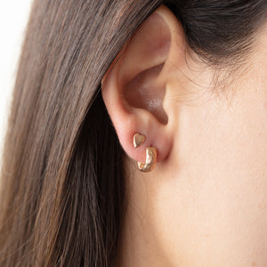 Model wearing mini-heart earrings in 18k yellow gold