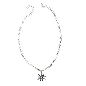 Top-down view of sterling silver Star Anise Necklace with emerald